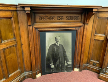 One of the fireplaces with the Latin Inscription ‘To Rule is to serve’ and a photograph of Principal Rendall.