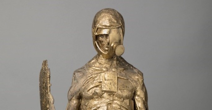 Bronze sculpture of police figure with baton, shield and gas mask.