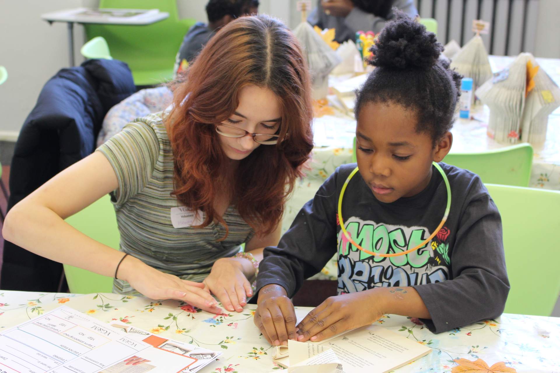 A volunteer helps a child in an activity sessions