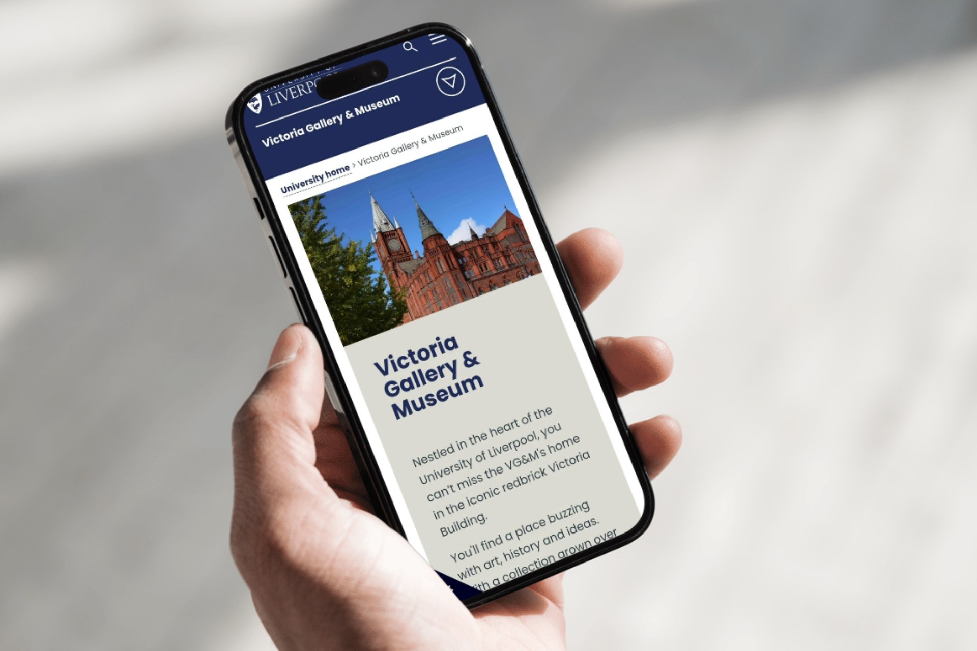 A close-up of a mobile phone with the VG&M website on the screen